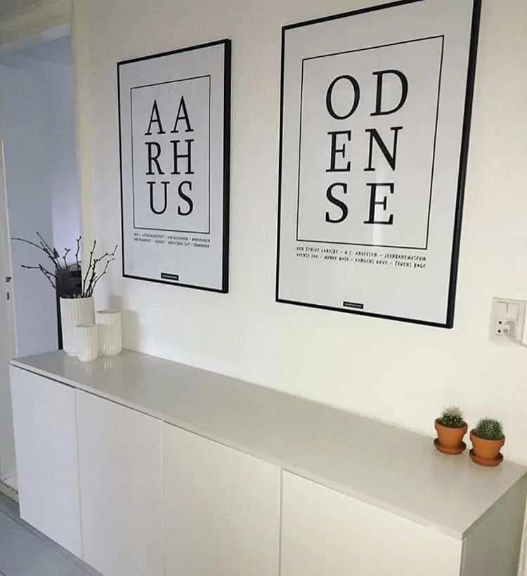 To by plakater med Århus og Odense hængende på hvid væg over tre skabe med hvide lyngbyvaser
