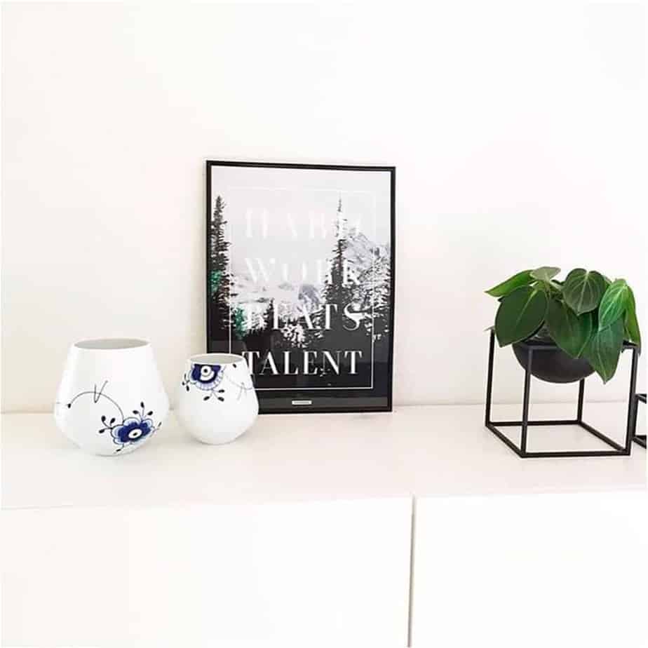Lys plakat med motiverende tekst ved vase og stueplante