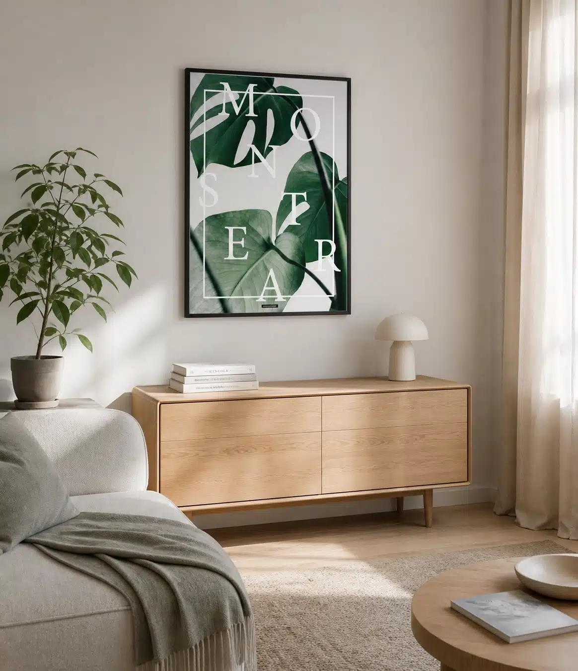 MONSTERA plakat i sort ramme over en lys egetræsskænk i en dansk stue med sofa, plante, tekstiler og naturligt dagslys.