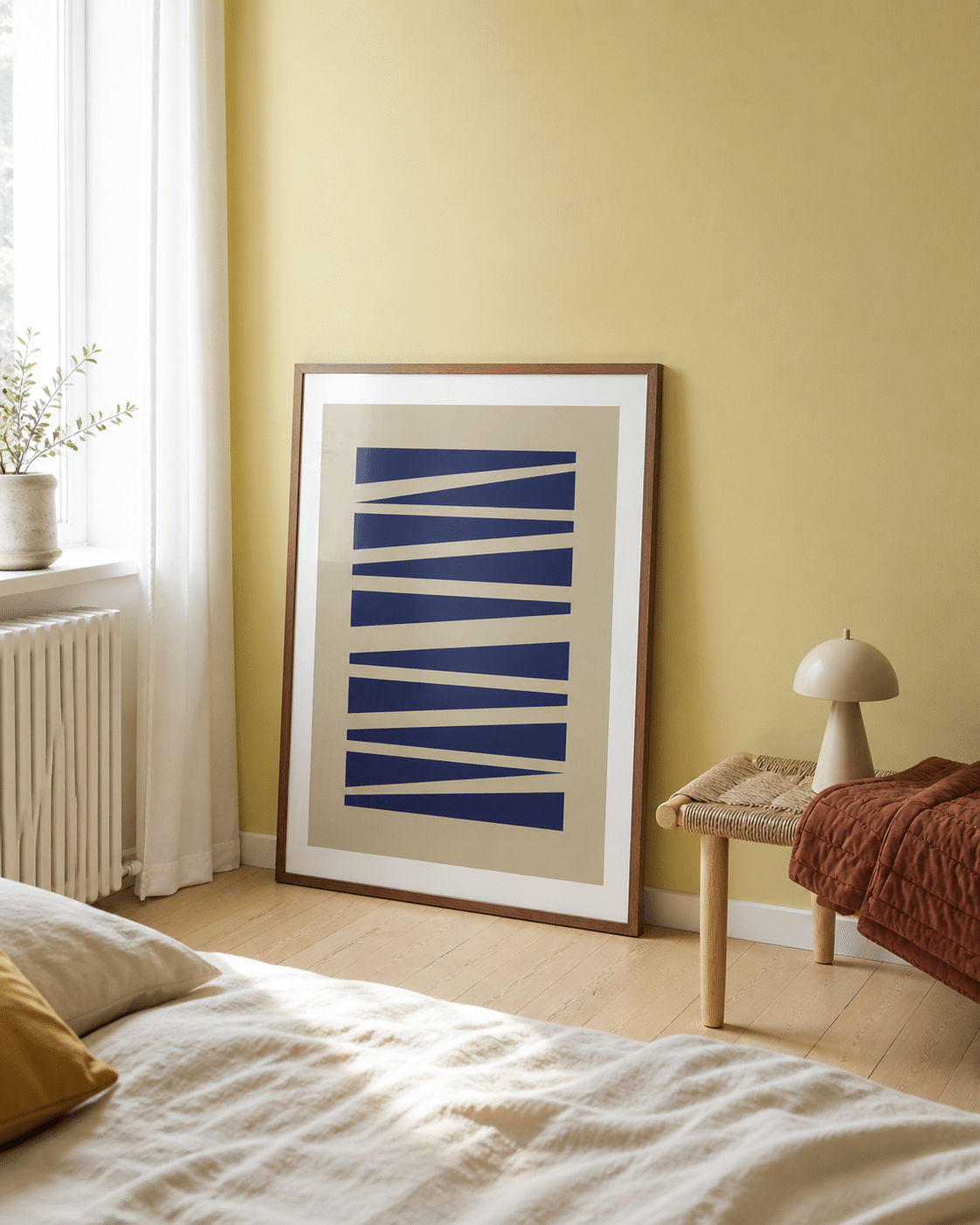 ABSTRAKT NO.1 plakat i valnødderamme i et lyst dansk soveværelse med gul væg, flettet bænk, rustfarvet tæppe og naturligt dagslys