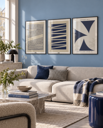 Blue Geometric plakatsæt med tre blå geometriske plakater i sorte aluminiumsrammer over en moderne sofa i en lys blå stue.