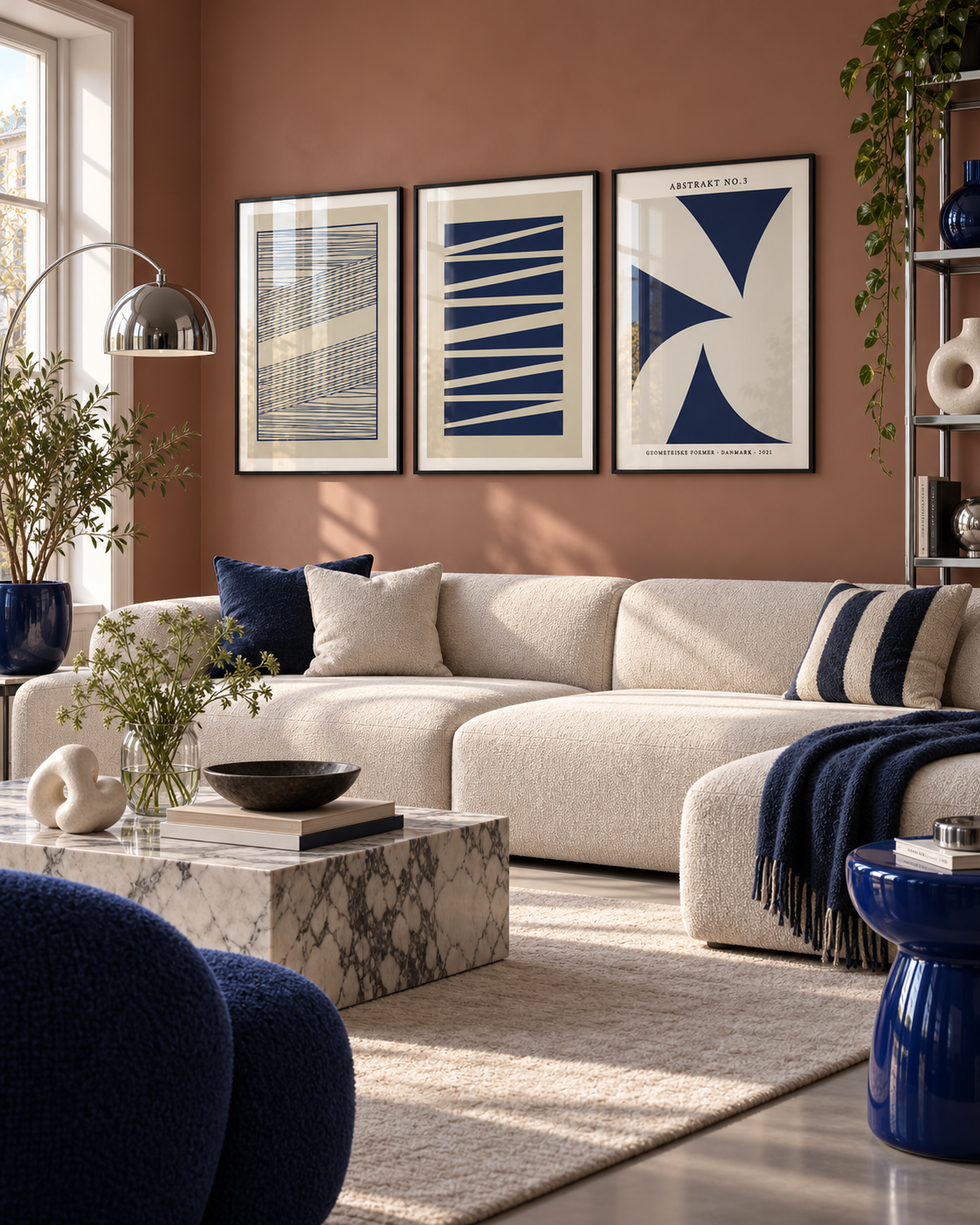 Blue Geometric plakatsæt med tre blå geometriske plakater i sorte aluminiumsrammer over en moderne sofa foran en terrakottafarvet væg.