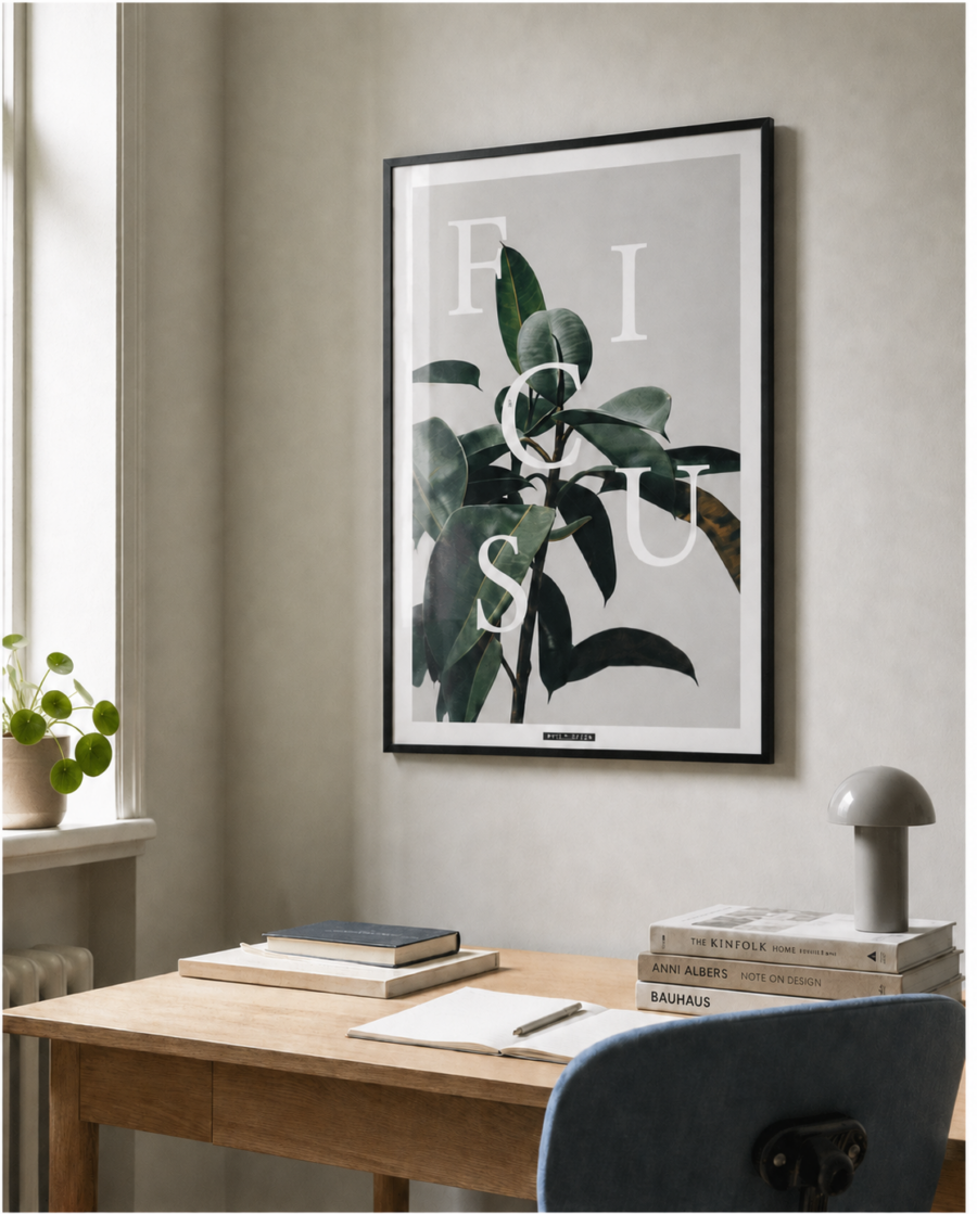 FICUS ELASTICA plakat i sort ramme over et lyst egetræsskrivebord med naturligt dagslys.