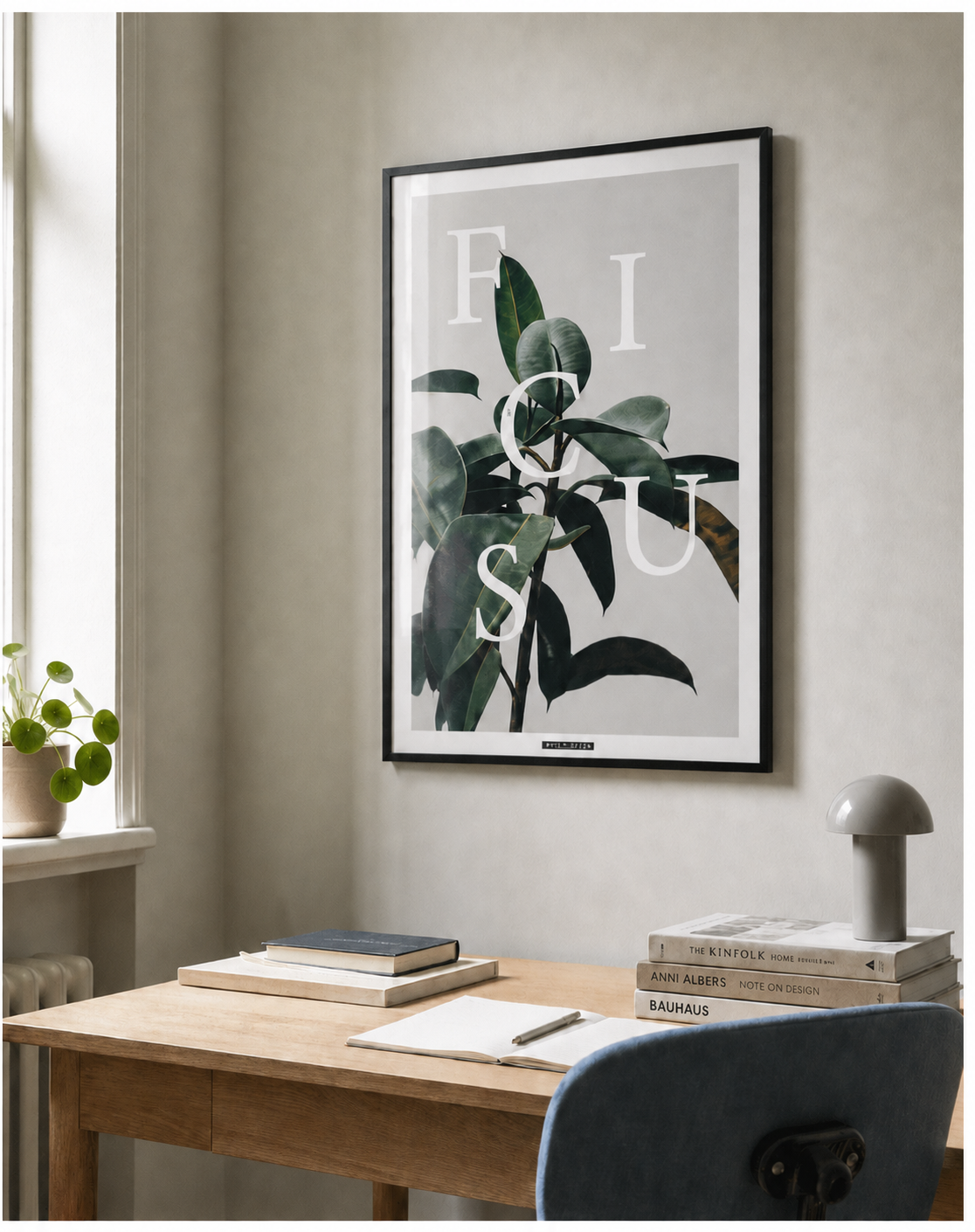 FICUS ELASTICA plakat i sort ramme over et lyst egetræsskrivebord med naturligt dagslys.