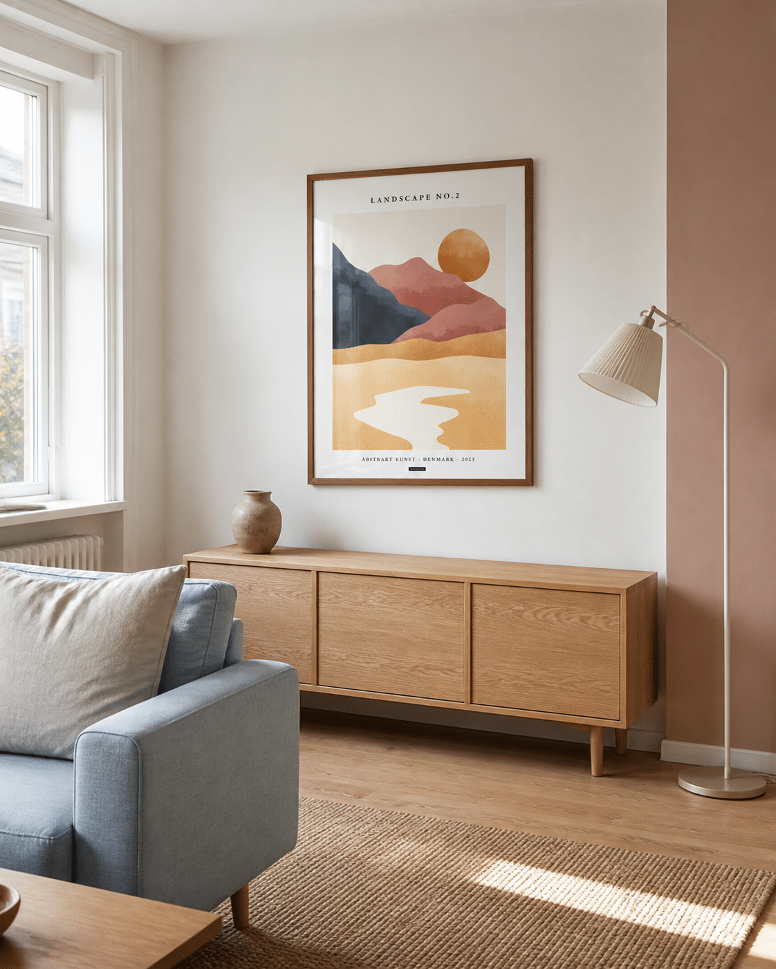 LANDSCAPE NO.2 plakat i valnøddefarvet ramme i en lys dansk stue med lyseblå sofa, egetræsskænk, rosa væg og dagslys
