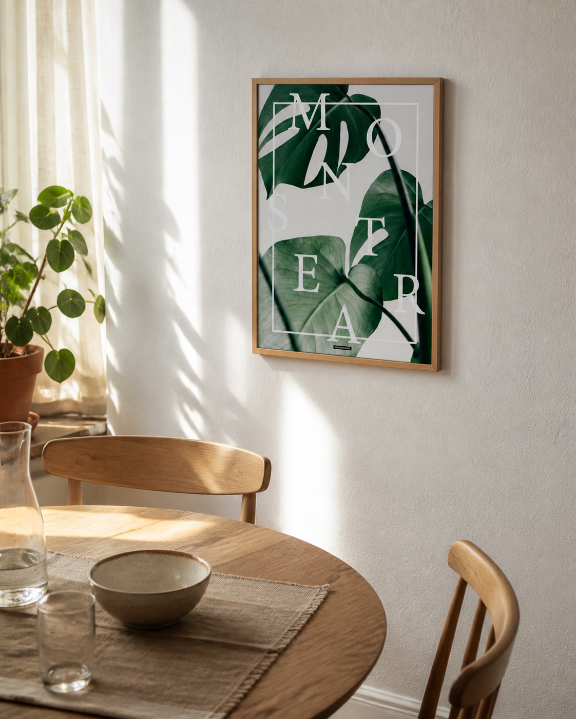Monstera plakat i egetraesramme hænger i en lys dansk spisestue med egetraesbord og naturligt dagslys.