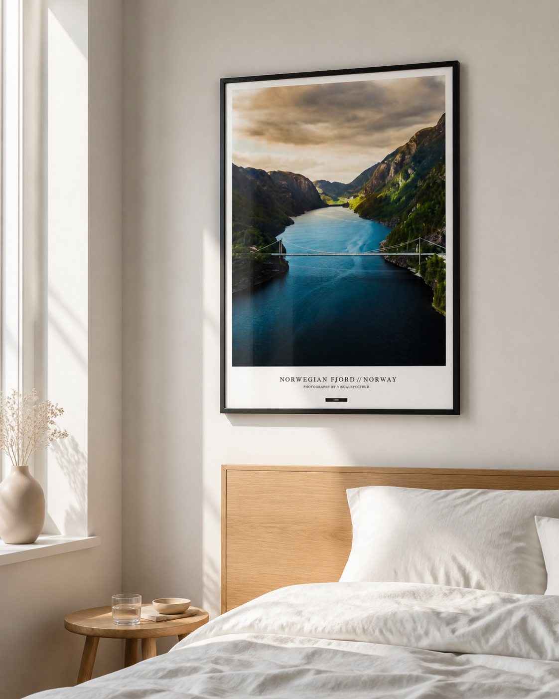 NORWEGIAN FJORD plakat i sort ramme over en lys egetræsseng i et nordisk soveværelse med dagslys.