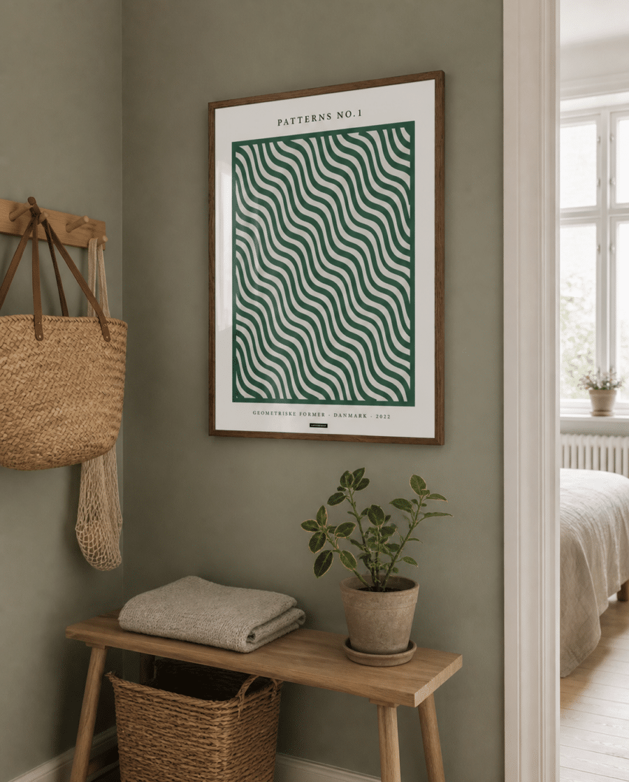 Patterns No.1-plakaten med grønne bølger i en varm træramme hænger på en grøn væg i en naturlig dansk entré med bænk, kurv og dagslys.