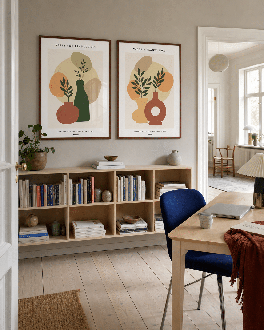 VASES AND PLANTS NO.1 og VASES AND PLANTS NO.2 plakater i valnødderammer i et lyst dansk kontor med bogreol, blå stol, egetræsbord og dagslys